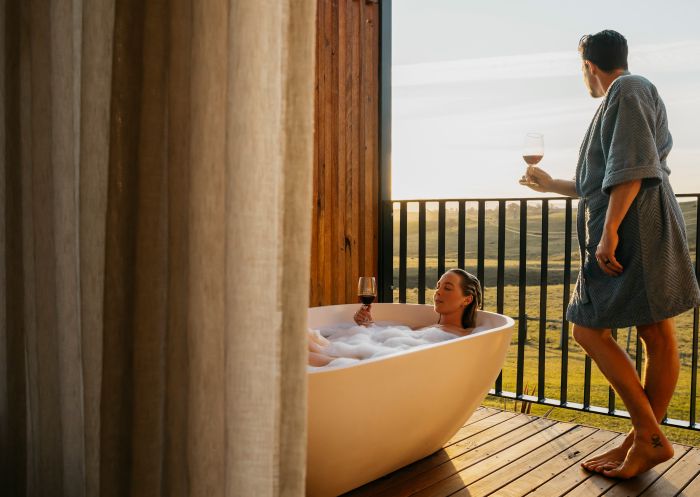 Couple enjoying bath and wine from balcony at Cupitt's Estate Villas, Ulladulla
